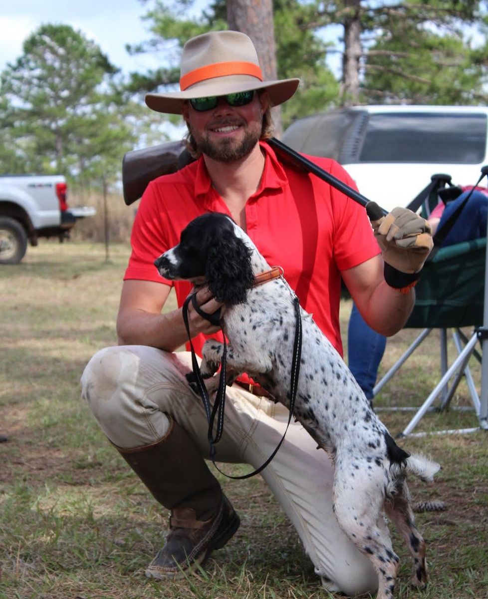 Josiah Austinson, owner and guide, kneeling with a spaniel and shotgun